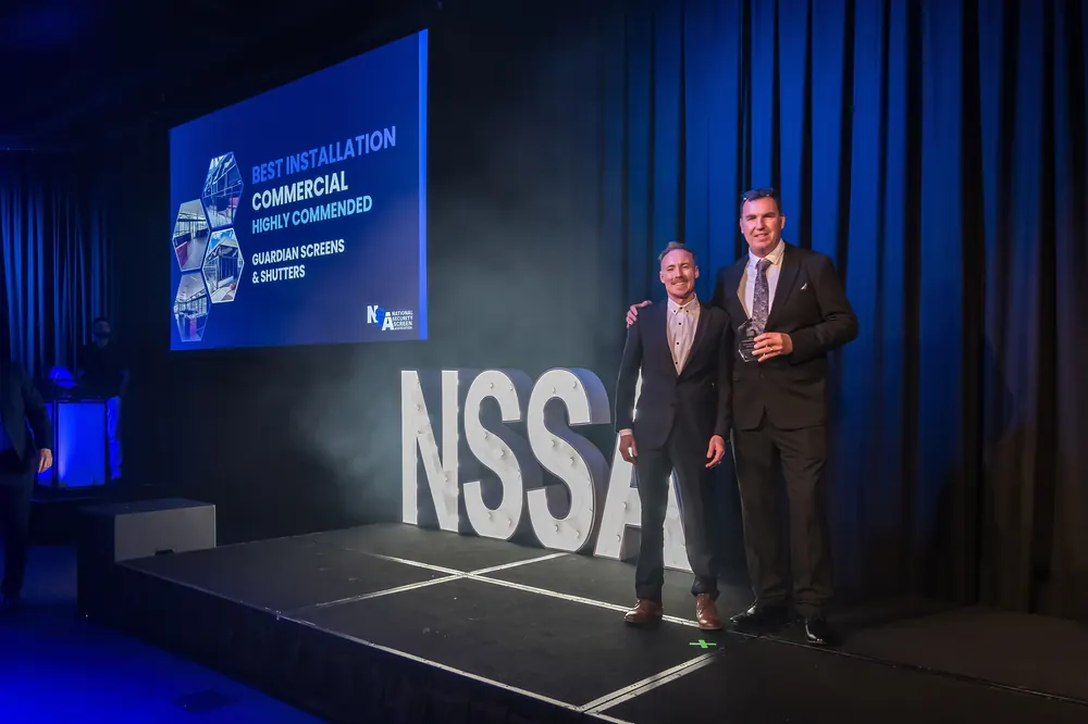 Guardian on stage at the NSSA awards, the screen behind reading Best Installation Commercial, Highly Commended, Guardian Screens & Shutters